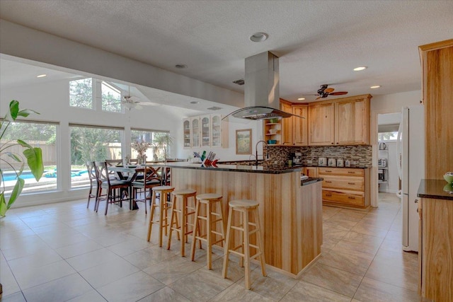 6022 Abilene Trl, Austin, TX 78749 - kitchen with a ceiling fan, island exhaust hood, a breakfast bar area, freestanding refrigerator, and tasteful backsplash
