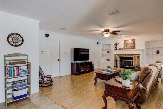 6022 Abilene Trl, Austin, TX 78749 - living room featuring a ceiling fan, ornamental molding, built in features, wood finished floors, and a brick fireplace
