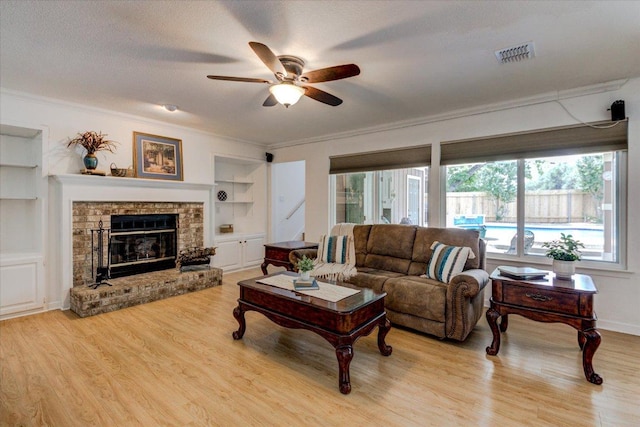 6022 Abilene Trl, Austin, TX 78749 - living room featuring built in shelves, a ceiling fan, crown molding, healthy amount of natural light, and light wood-style floors