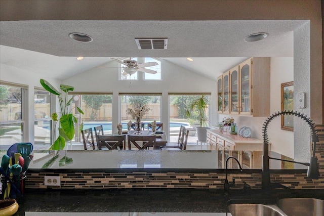 6022 Abilene Trl, Austin, TX 78749 - kitchen featuring ceiling fan, lofted ceiling, glass insert cabinets, a textured ceiling, and light brown cabinets