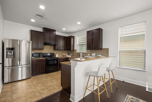 11325 Kirkland Hill Path, Austin, TX 78754 - kitchen with appliances with stainless steel finishes, under cabinet range hood, dark brown cabinets, decorative backsplash, and recessed lighting