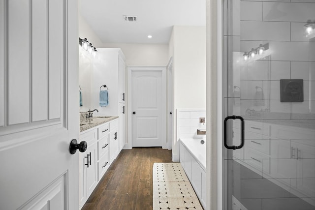 121 Gloria Blvd, Smithville, TX 78957 - bathroom featuring wood finished floors, a bath, a stall shower, vanity, and recessed lighting