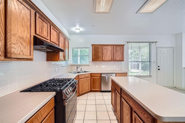 4712 Ramies Run, Austin, TX 78749 - kitchen featuring stainless steel dishwasher, range with gas stovetop, under cabinet range hood, and brown cabinetry