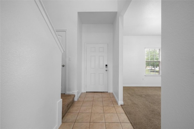 hall featuring light tile patterned floors, light colored carpet, and baseboards