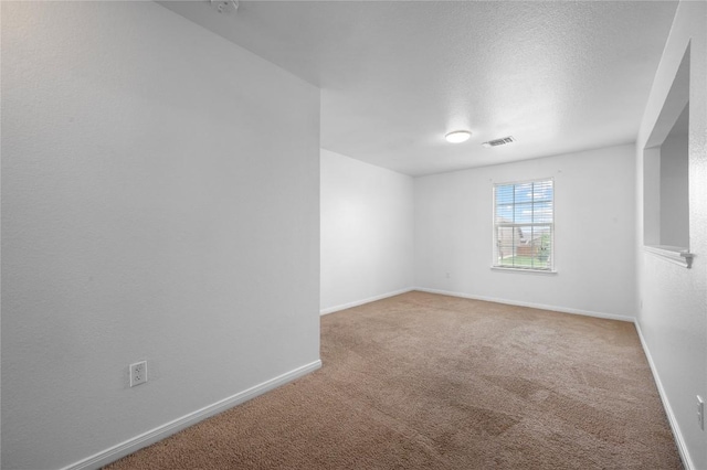 spare room featuring carpet flooring, baseboards, and a textured ceiling