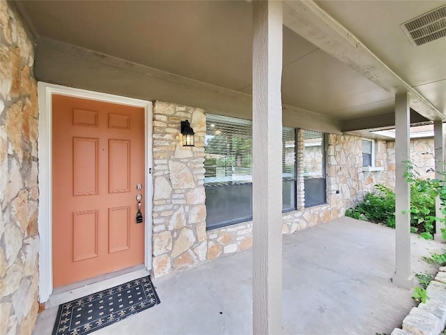 9512 Meadowheath Dr, Austin, TX 78729 - view of exterior entry featuring stone siding and a porch