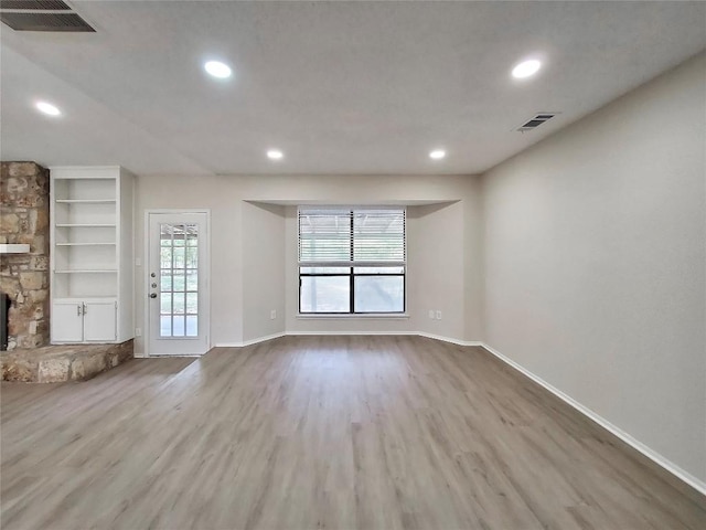9512 Meadowheath Dr, Austin, TX 78729 - unfurnished living room with wood finished floors, recessed lighting, a stone fireplace, baseboards, and built in features