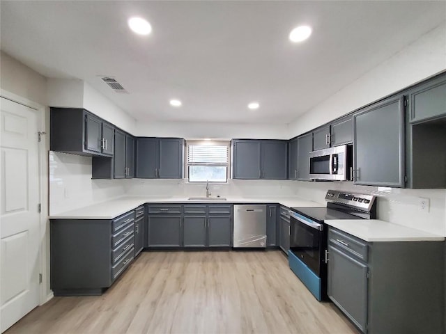 9512 Meadowheath Dr, Austin, TX 78729 - kitchen featuring appliances with stainless steel finishes, a sink, light wood-type flooring, recessed lighting, and light countertops