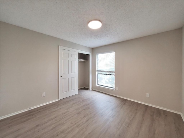 9512 Meadowheath Dr, Austin, TX 78729 - unfurnished bedroom featuring wood finished floors, baseboards, a textured ceiling, and a closet