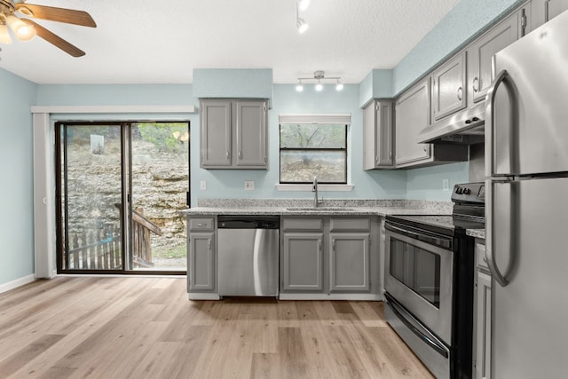 21459 Coyote Trl Unit A2, Lago Vista, TX 78645 - kitchen featuring stainless steel appliances, gray cabinets, a sink, under cabinet range hood, and light wood-style flooring