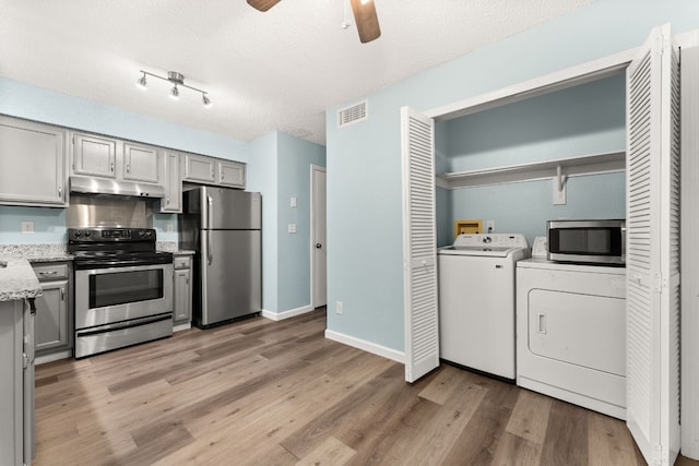 21459 Coyote Trl Unit A2, Lago Vista, TX 78645 - kitchen featuring appliances with stainless steel finishes, under cabinet range hood, independent washer and dryer, gray cabinetry, and a textured ceiling