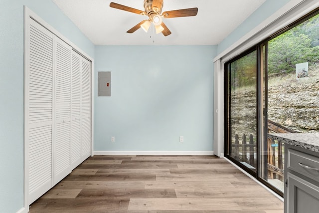 21459 Coyote Trl Unit A2, Lago Vista, TX 78645 - unfurnished bedroom with light wood-style flooring, access to exterior, baseboards, electric panel, and a ceiling fan