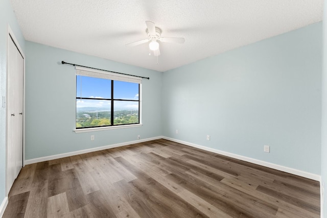 21459 Coyote Trl Unit A2, Lago Vista, TX 78645 - unfurnished bedroom featuring wood finished floors, a closet, baseboards, a ceiling fan, and a textured ceiling