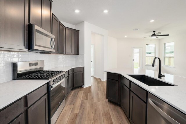 4923 Mozzafiato Ln, Round Rock, TX 78665 - kitchen featuring stainless steel appliances, a sink, decorative backsplash, light wood-style flooring, and ceiling fan