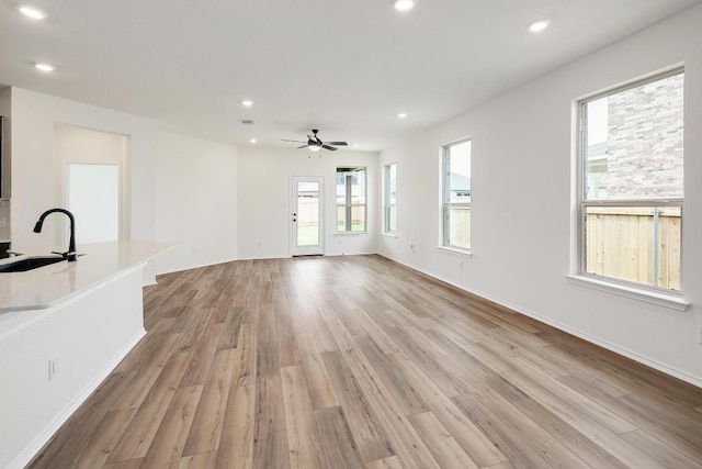 4923 Mozzafiato Ln, Round Rock, TX 78665 - unfurnished living room featuring a sink, light wood-style floors, recessed lighting, ceiling fan, and baseboards
