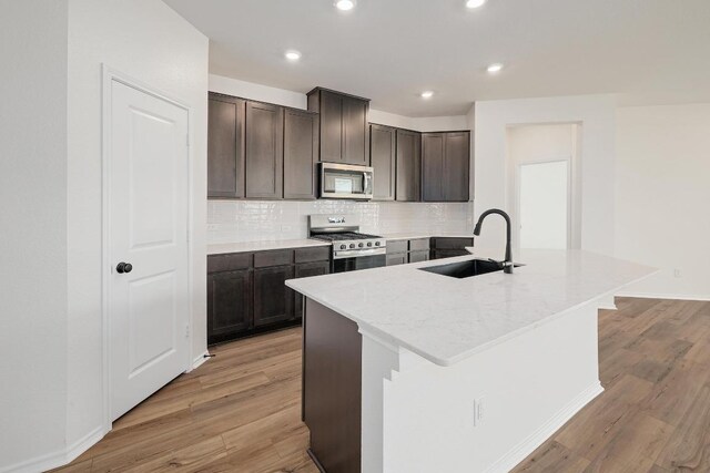 4923 Mozzafiato Ln, Round Rock, TX 78665 - kitchen featuring appliances with stainless steel finishes, a sink, light wood-style flooring, backsplash, and recessed lighting