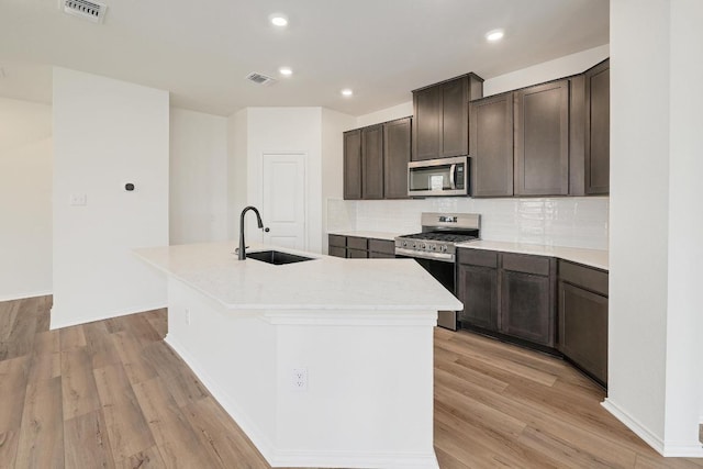4923 Mozzafiato Ln, Round Rock, TX 78665 - kitchen featuring appliances with stainless steel finishes, a sink, a kitchen island with sink, light wood-style floors, and recessed lighting