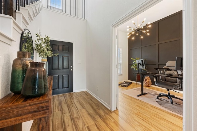 707 Sugar Cane Rd, Buda, TX 78610 - foyer featuring wood finished floors, a chandelier, a high ceiling, baseboards, and a decorative wall