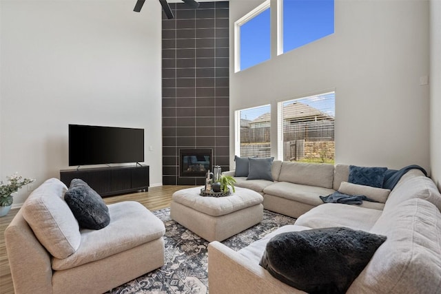 707 Sugar Cane Rd, Buda, TX 78610 - living room with a towering ceiling, wood finished floors, a ceiling fan, a fireplace, and baseboards