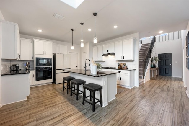 707 Sugar Cane Rd, Buda, TX 78610 - kitchen with black appliances, dark countertops, under cabinet range hood, backsplash, and recessed lighting