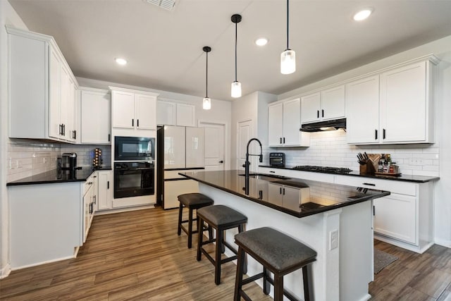 707 Sugar Cane Rd, Buda, TX 78610 - kitchen featuring black appliances, under cabinet range hood, a sink, dark countertops, and recessed lighting