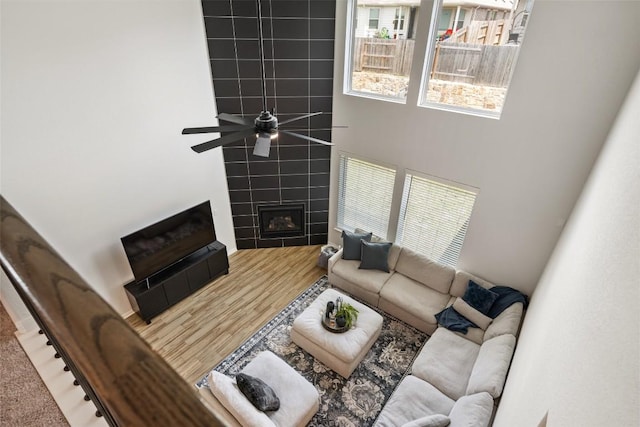 707 Sugar Cane Rd, Buda, TX 78610 - living area featuring a towering ceiling, a tiled fireplace, ceiling fan, and wood finished floors