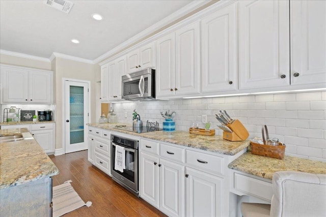 1409 Old Mill Rd, Salado, TX 76571 - kitchen with stainless steel appliances, crown molding, white cabinetry, dark wood-style flooring, and backsplash