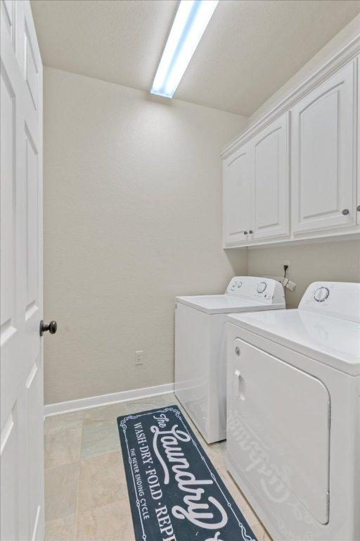 1409 Old Mill Rd, Salado, TX 76571 - laundry room featuring washing machine and dryer, cabinet space, and baseboards