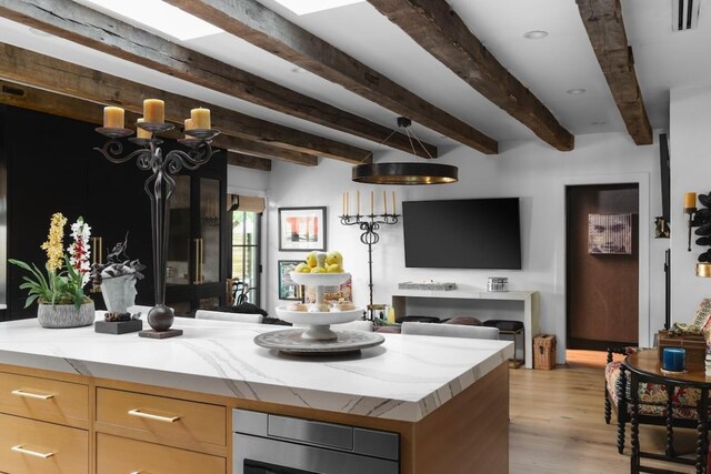 713 E 32nd St, Austin, TX 78705 - kitchen featuring open floor plan, beam ceiling, light wood finished floors, and light stone counters