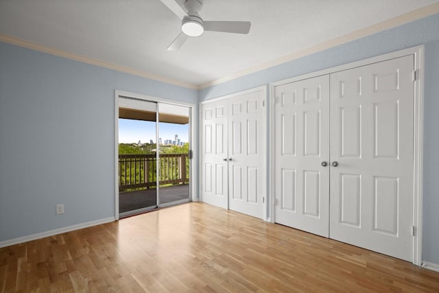 2450 Wickersham Ln Unit M1318, Austin, TX 78741 - unfurnished bedroom featuring access to exterior, crown molding, multiple closets, wood finished floors, and baseboards