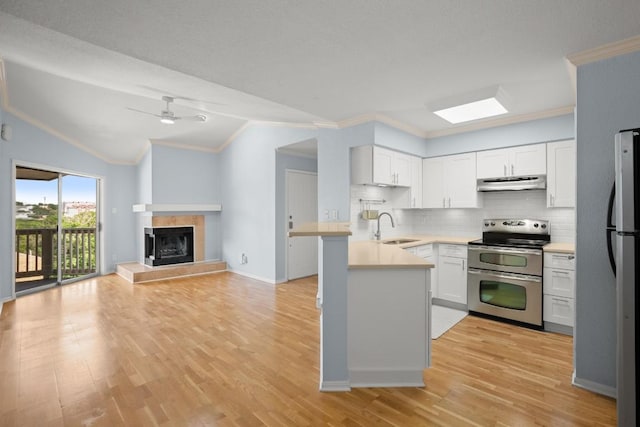 2450 Wickersham Ln Unit M1318, Austin, TX 78741 - kitchen featuring stainless steel appliances, range hood, a sink, a peninsula, and vaulted ceiling