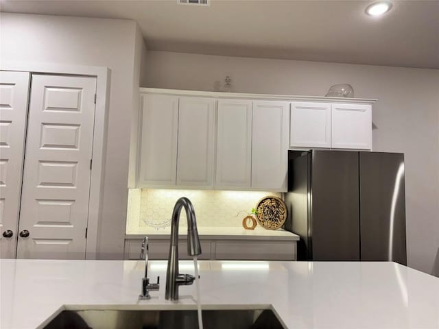 1162 Thicket Ln, New Braunfels, TX 78132 - kitchen with freestanding refrigerator, white cabinets, a sink, light countertops, and backsplash