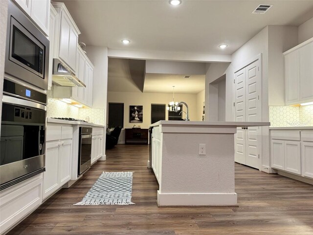 1162 Thicket Ln, New Braunfels, TX 78132 - kitchen with appliances with stainless steel finishes, a chandelier, white cabinets, decorative backsplash, and a kitchen island with sink