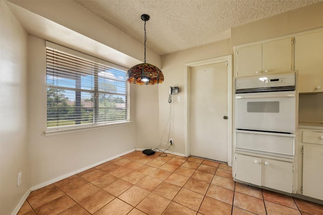 105 E St Johns Ave, Austin, TX 78752 - unfurnished dining area with a textured ceiling, light tile patterned floors, and baseboards