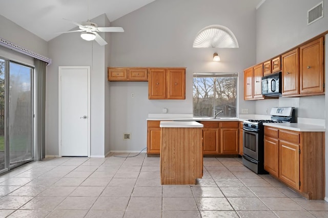 16901 Dashwood Creek Dr, Pflugerville, TX 78660 - kitchen with stainless steel gas range oven, black microwave, high vaulted ceiling, healthy amount of natural light, and light countertops