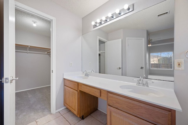 16901 Dashwood Creek Dr, Pflugerville, TX 78660 - bathroom with double vanity, a textured ceiling, tile patterned flooring, a walk in closet, and ceiling fan