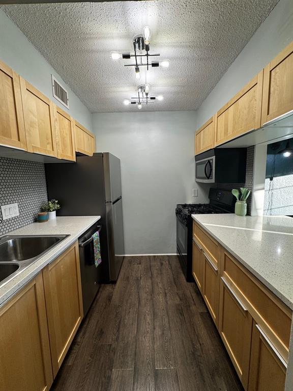 2425 Ashdale Dr Unit 101, Austin, TX 78757 - kitchen featuring black gas range, stainless steel dishwasher, dark wood-type flooring, light countertops, and a sink