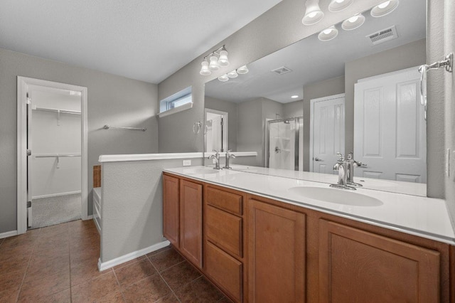 full bath featuring a stall shower, double vanity, baseboards, and tile patterned floors