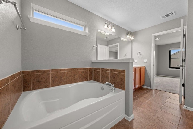 bathroom with a garden tub, tile patterned floors, vanity, and baseboards