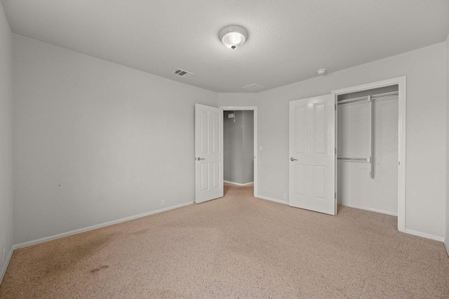 unfurnished bedroom featuring carpet, baseboards, and a closet