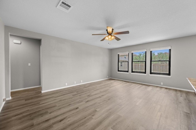 spare room with ceiling fan, wood finished floors, baseboards, and a textured ceiling
