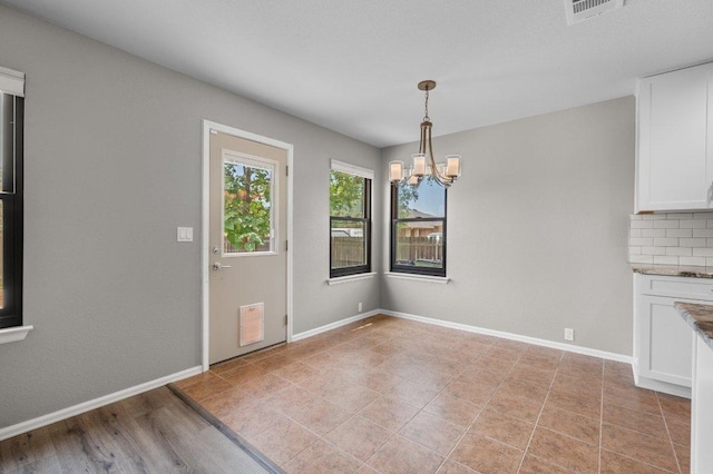 unfurnished dining area with a chandelier and baseboards