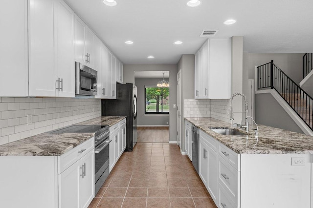 141 Snowy Egret Ln, Leander, TX 78641 - kitchen featuring stainless steel appliances, a sink, a peninsula, white cabinetry, and recessed lighting