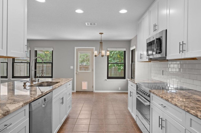141 Snowy Egret Ln, Leander, TX 78641 - kitchen featuring appliances with stainless steel finishes, baseboards, a sink, tasteful backsplash, and white cabinetry