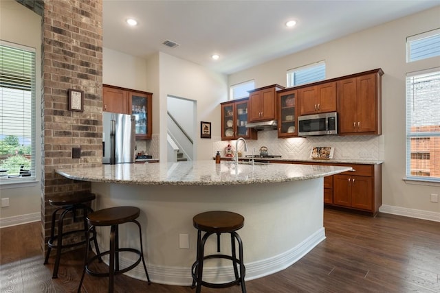 152 Baretta Loop, Buda, TX 78610 - kitchen with appliances with stainless steel finishes, a sink, brown cabinetry, decorative backsplash, and dark wood-style floors