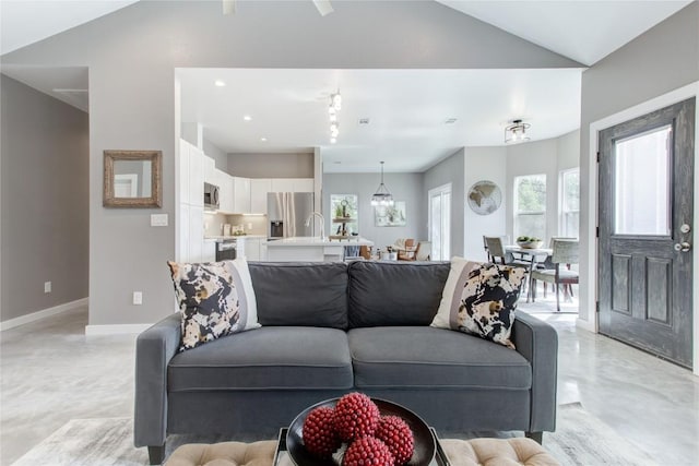 living area with finished concrete flooring, vaulted ceiling, baseboards, and recessed lighting