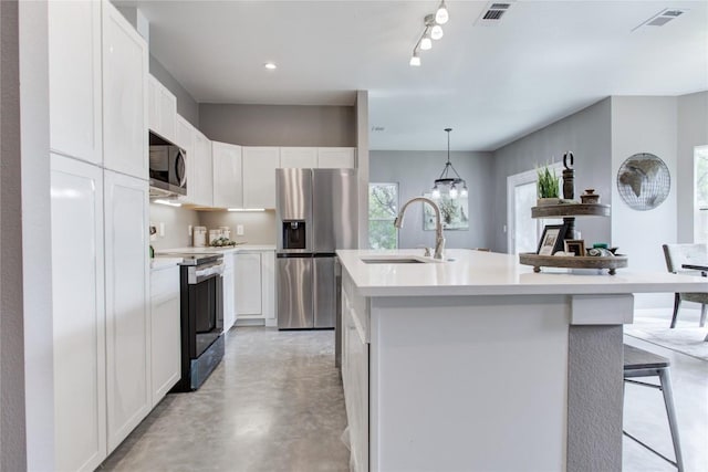 kitchen featuring stainless steel appliances, a sink, finished concrete floors, light countertops, and white cabinets