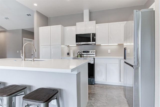 kitchen with stainless steel appliances, a sink, finished concrete floors, white cabinetry, and light countertops