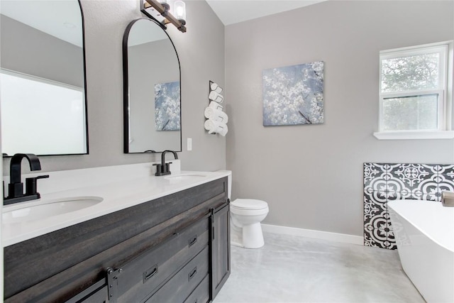 full bath featuring a freestanding bath, baseboards, concrete floors, double vanity, and toilet