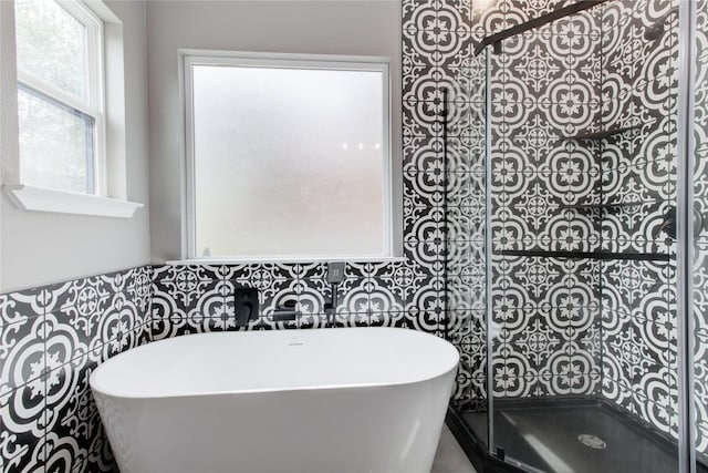 full bathroom featuring a freestanding bath, tiled shower, and tile walls